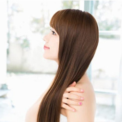 Side profile of a woman with long, healthy brown hair after hair loss treatment